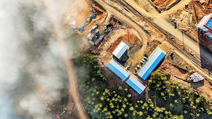Aerial view of a graded construction site with new roads, pads, and site trailers