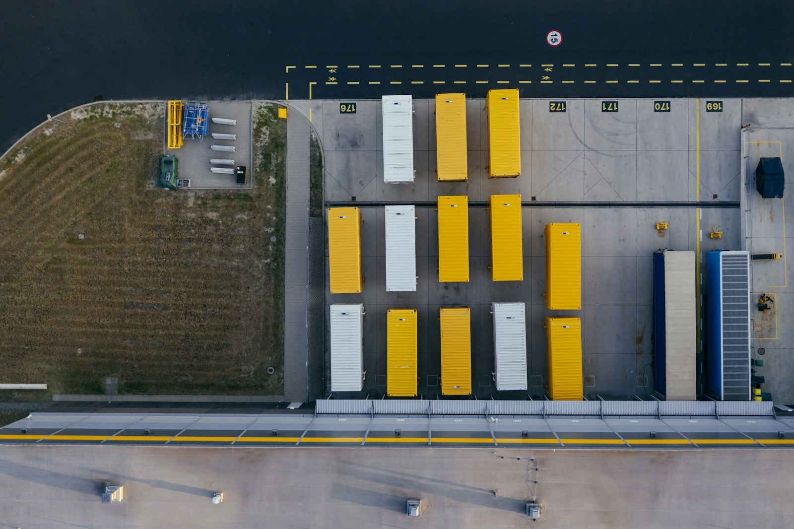 Aerial view of a paved truck yard with rows of parked semi-trailers